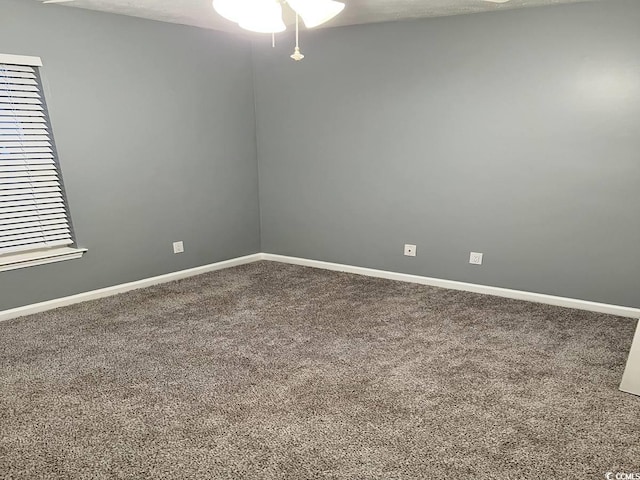 empty room featuring carpet flooring, baseboards, and ceiling fan
