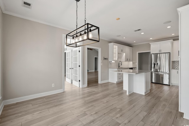 kitchen with decorative backsplash, visible vents, a sink, stainless steel fridge, and ornamental molding
