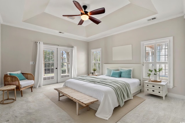 bedroom with a raised ceiling, light carpet, french doors, and access to exterior