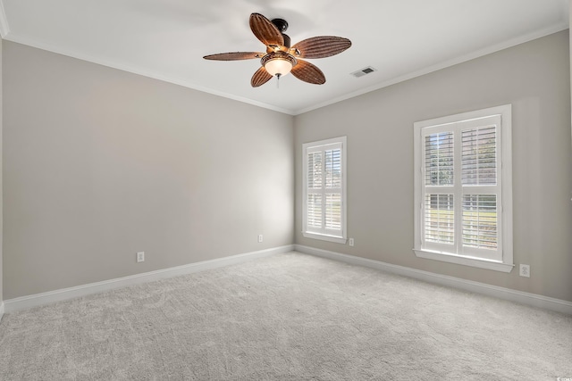 carpeted spare room with visible vents, a ceiling fan, baseboards, and crown molding