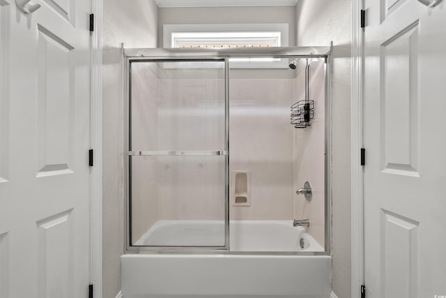 full bath with a textured wall and shower / bath combination with glass door