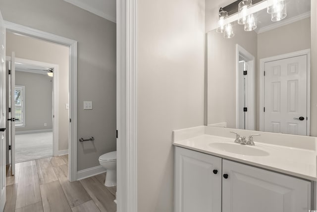 bathroom featuring crown molding, wood finished floors, vanity, baseboards, and toilet