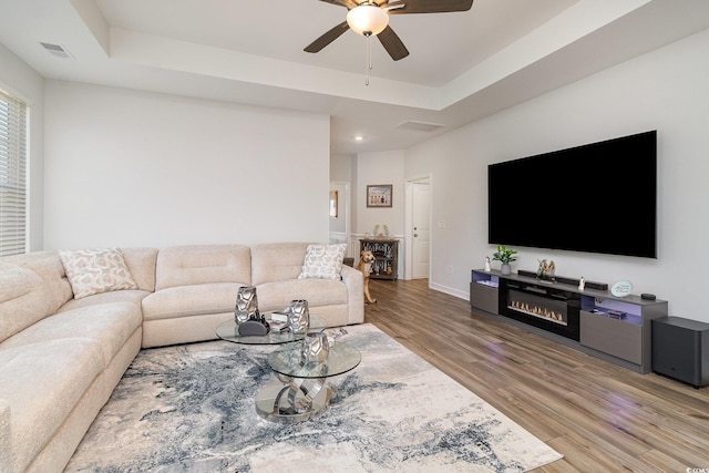 294 Portofino Dr, Myrtle Beach, SC 29579 - living room with a ceiling fan, light wood-type flooring, a raised ceiling, a glass covered fireplace, and recessed lighting