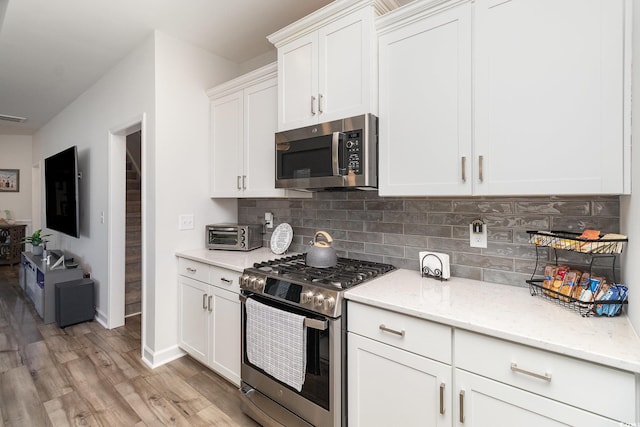 294 Portofino Dr, Myrtle Beach, SC 29579 - kitchen with stainless steel appliances, decorative backsplash, light wood-style flooring, and white cabinetry