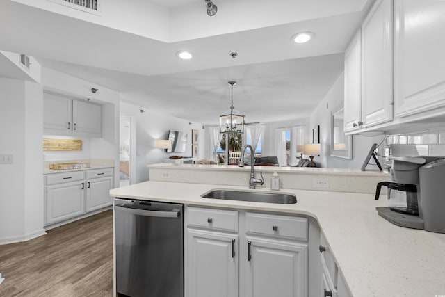 kitchen with a peninsula, open floor plan, light countertops, a sink, and dishwasher