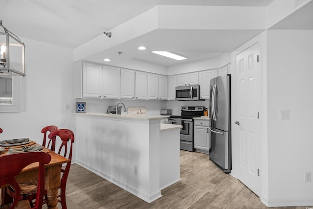 kitchen featuring appliances with stainless steel finishes, light countertops, light wood finished floors, recessed lighting, and white cabinetry