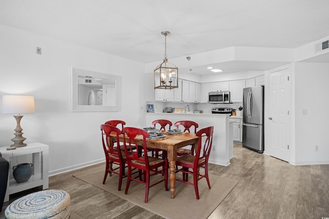 dining area featuring baseboards, light wood-style flooring, a notable chandelier, and visible vents