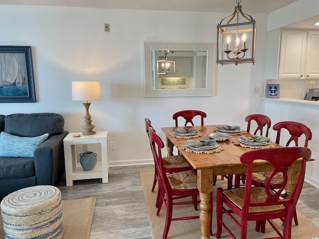 dining area with baseboards, a notable chandelier, and light wood-type flooring