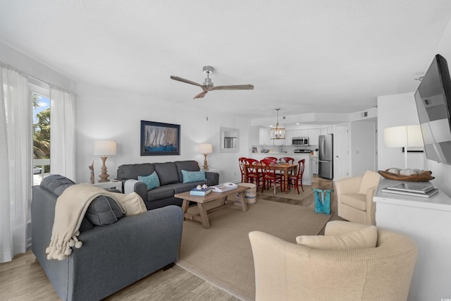 living room with a ceiling fan and light wood-style flooring