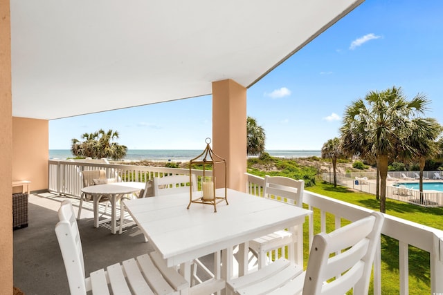 deck featuring a fenced in pool, outdoor dining space, and a water view