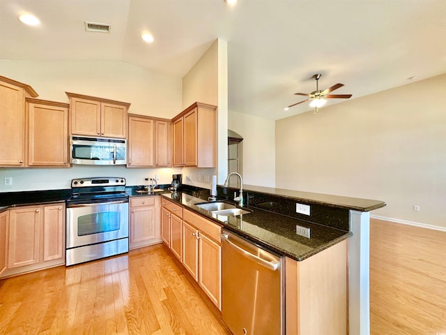 1612 Fairforest Ct, Conway, SC 29526 - kitchen featuring appliances with stainless steel finishes, light wood-type flooring, a peninsula, lofted ceiling, and dark stone counters