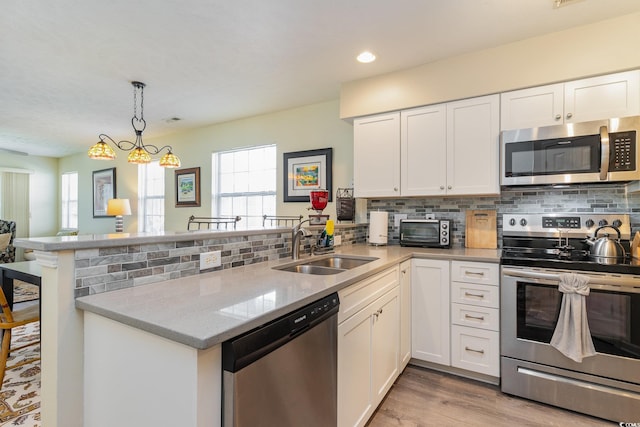 478 Pinehurst Ln Unit 17D, Pawleys Island, SC 29585 - kitchen with stainless steel appliances, a peninsula, a sink, white cabinets, and light stone countertops