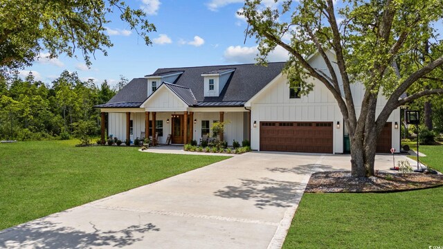 modern farmhouse style home with metal roof, a front yard, a standing seam roof, board and batten siding, and driveway