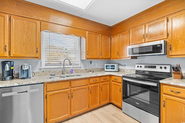 600-B 43rd Ave S, North Myrtle Beach, SC 29582 - kitchen featuring appliances with stainless steel finishes, light wood finished floors, light stone counters, and brown cabinets