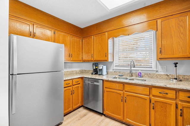 600-B 43rd Ave S, North Myrtle Beach, SC 29582 - kitchen with appliances with stainless steel finishes, light wood-style flooring, brown cabinets, and light stone countertops