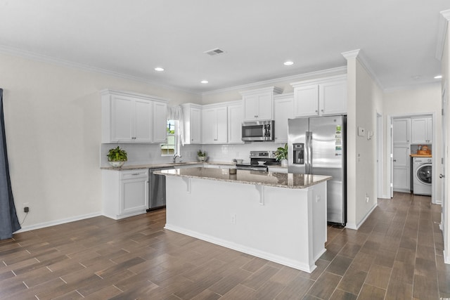 100 Marblehead Dr, Little River, SC 29566 - kitchen featuring appliances with stainless steel finishes, washer / clothes dryer, a kitchen island, white cabinets, and dark wood-type flooring