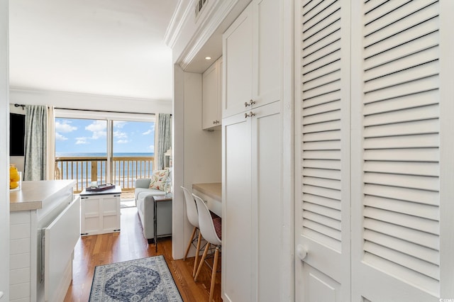 washroom featuring light wood-style flooring, visible vents, crown molding, and a water view
