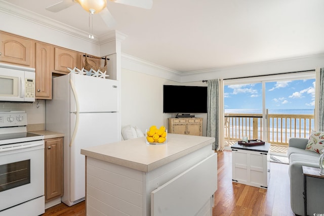 kitchen with light countertops, crown molding, white appliances, light wood-style floors, and a center island