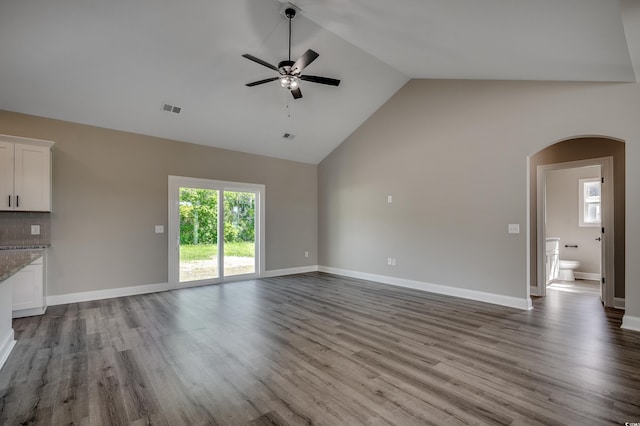 unfurnished living room featuring arched walkways, a ceiling fan, wood finished floors, baseboards, and high vaulted ceiling