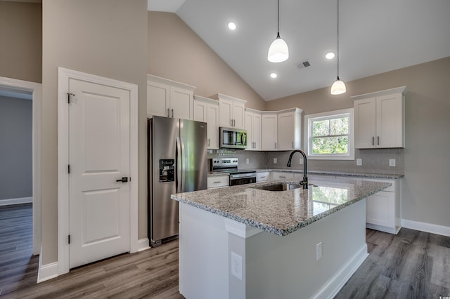 kitchen with stainless steel appliances, a sink, white cabinetry, wood finished floors, and light stone counters