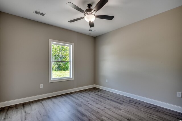 spare room with dark wood-style floors, baseboards, and a ceiling fan