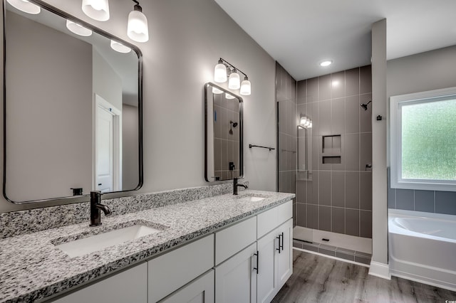 bathroom featuring tiled shower, double vanity, a garden tub, and wood finished floors