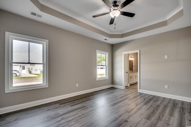 unfurnished room with a raised ceiling, dark wood-type flooring, ornamental molding, ceiling fan, and baseboards