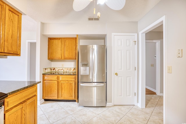 1161 Ganton Way, Myrtle Beach, SC 29588 - kitchen with stainless steel refrigerator with ice dispenser, light tile patterned floors, dark stone counters, brown cabinets, and a textured ceiling