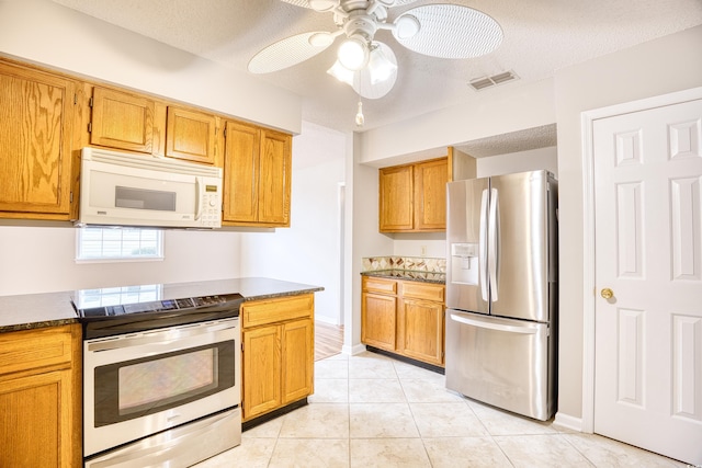 1161 Ganton Way, Myrtle Beach, SC 29588 - kitchen with stainless steel appliances, a textured ceiling, light tile patterned floors, ceiling fan, and brown cabinetry