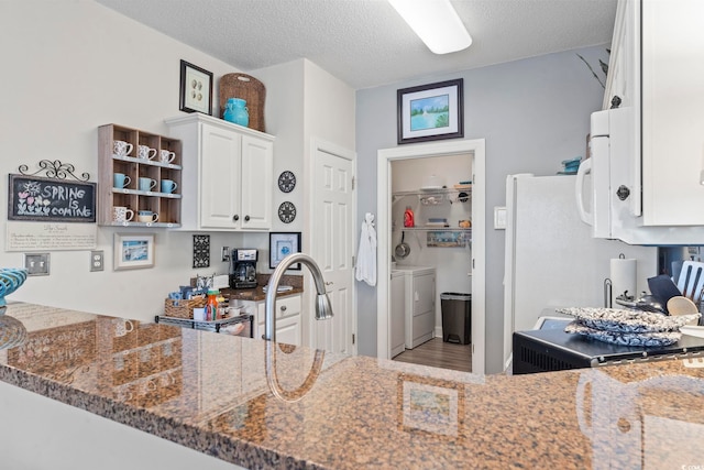 5050 Belleglen Ct Unit 102, Myrtle Beach, SC 29579 - kitchen with a textured ceiling, a sink, dark stone countertops, washing machine and clothes dryer, and white cabinets