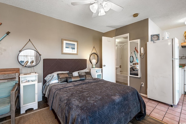 bedroom featuring ceiling fan, tile patterned flooring, freestanding refrigerator, and a textured ceiling