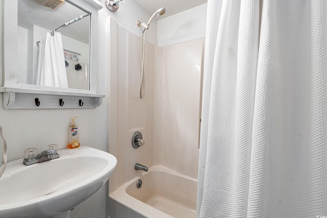 full bathroom featuring a sink, a textured ceiling, and shower / bath combination with curtain