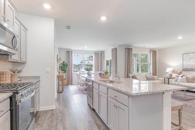kitchen featuring a sink, stainless steel appliances, open floor plan, a breakfast bar area, and light wood-style flooring