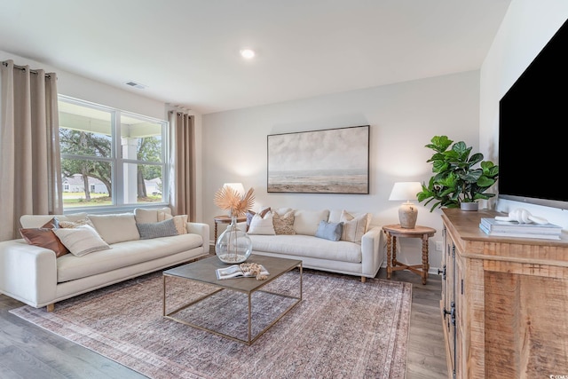 living room with recessed lighting, visible vents, and wood finished floors