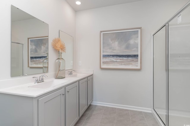 bathroom with a shower stall, double vanity, tile patterned floors, and baseboards