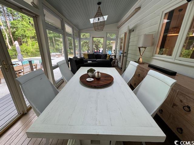 sunroom / solarium with french doors, wood finished floors, and a chandelier