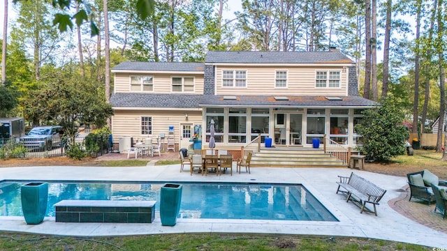 rear view of property with a sunroom, fence, a patio, and outdoor dining space
