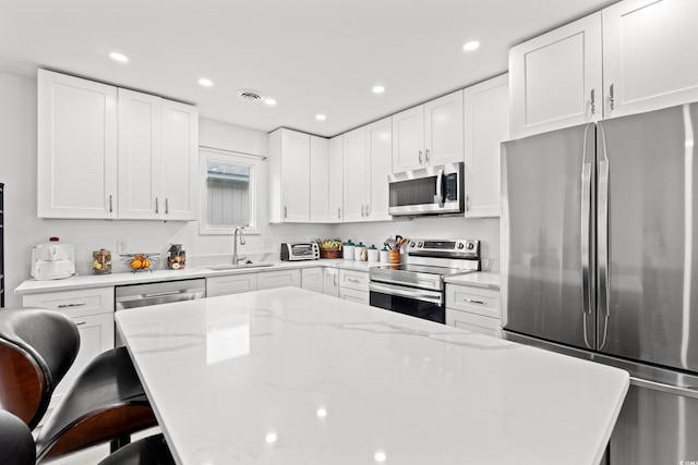 207 Fox Ln, Murrells Inlet, SC 29576 - kitchen with a sink, a kitchen breakfast bar, appliances with stainless steel finishes, visible vents, and white cabinets