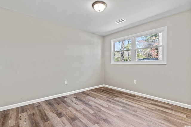 spare room featuring baseboards and wood finished floors