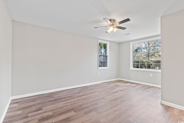 empty room with ceiling fan, wood finished floors, and baseboards