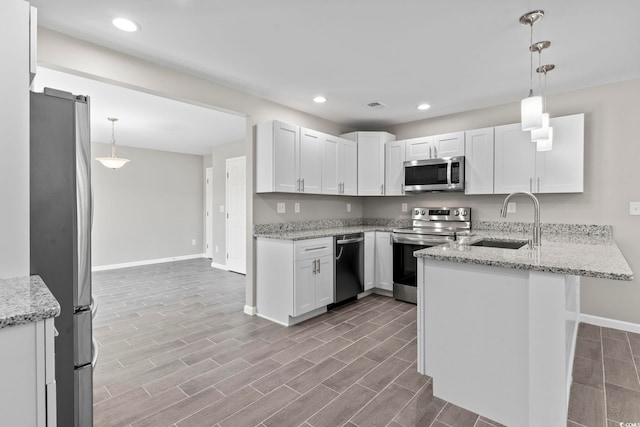 kitchen featuring stainless steel appliances, baseboards, a sink, a peninsula, and recessed lighting