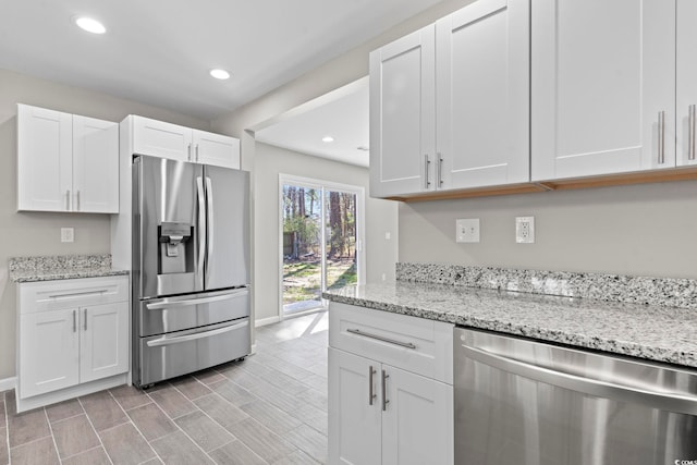 kitchen with appliances with stainless steel finishes, white cabinets, baseboards, light stone countertops, and recessed lighting