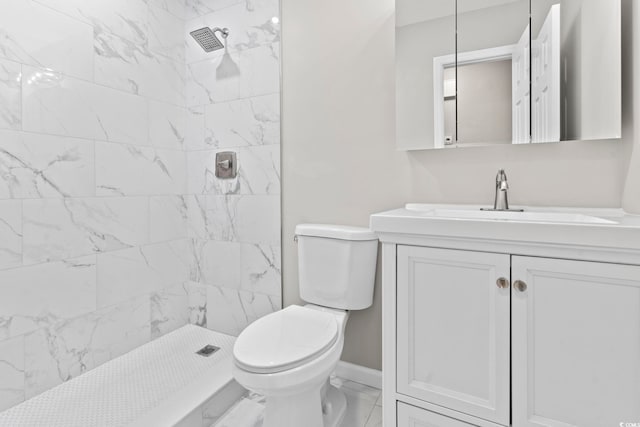 bathroom featuring toilet, vanity, tiled shower, baseboards, and marble look tiles