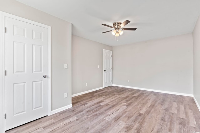 spare room with a ceiling fan, wood finished floors, and baseboards