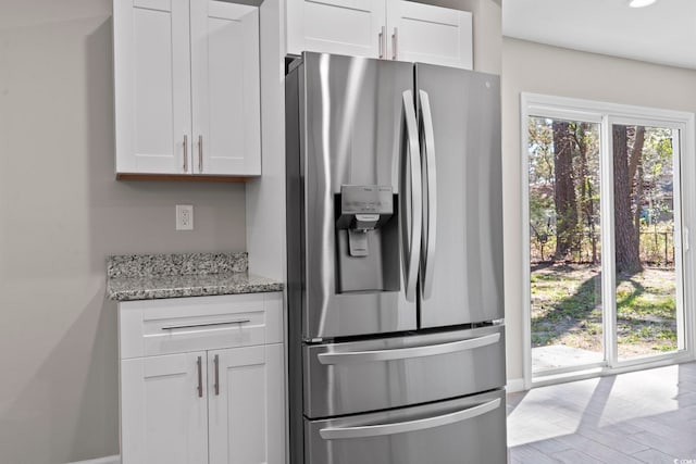 kitchen with stainless steel fridge with ice dispenser, white cabinetry, light stone countertops, baseboards, and recessed lighting
