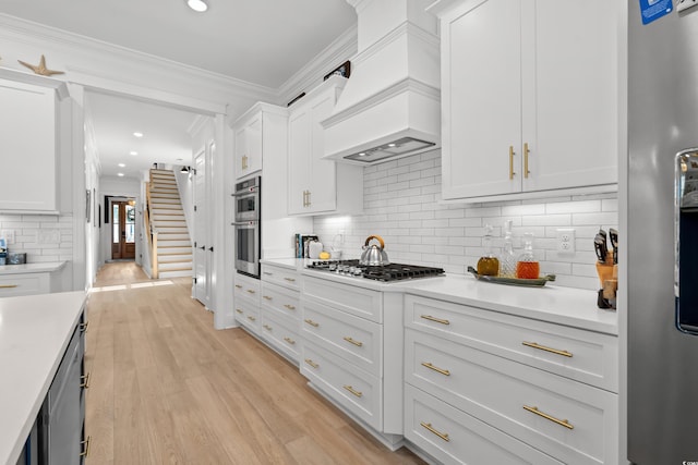 849 Crystal Water Way, Myrtle Beach, SC 29579 - kitchen featuring appliances with stainless steel finishes, custom range hood, light countertops, white cabinetry, and tasteful backsplash