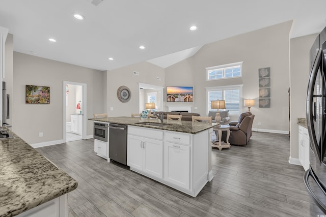 1109 Bonnet Dr, North Myrtle Beach, SC 29582 - kitchen with appliances with stainless steel finishes, open floor plan, stone countertops, a kitchen island with sink, and white cabinets