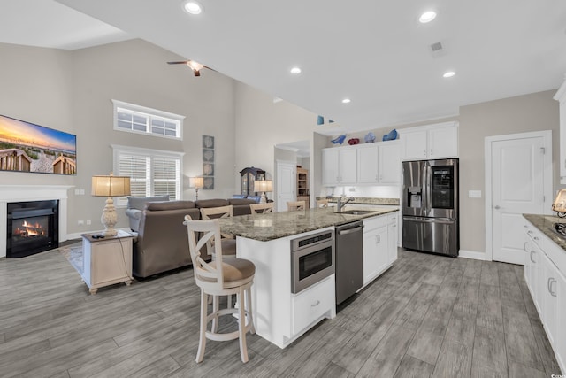 1109 Bonnet Dr, North Myrtle Beach, SC 29582 - kitchen with stainless steel appliances, open floor plan, a fireplace with flush hearth, a kitchen island with sink, and high vaulted ceiling