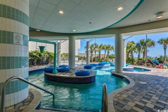 community pool with a patio area, a community hot tub, and fence