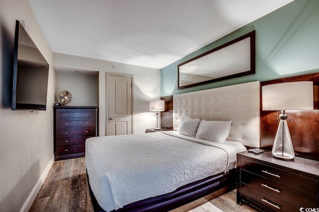 bedroom with wood finished floors, baseboards, and a textured ceiling